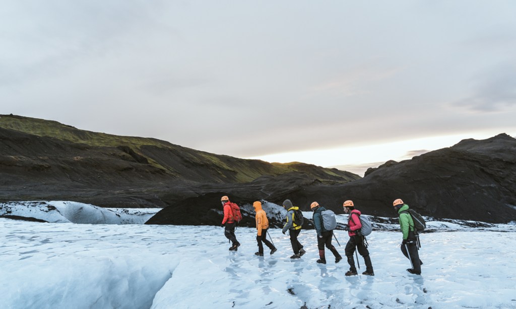 A group of trekkers walk on an ice-covered landscape.