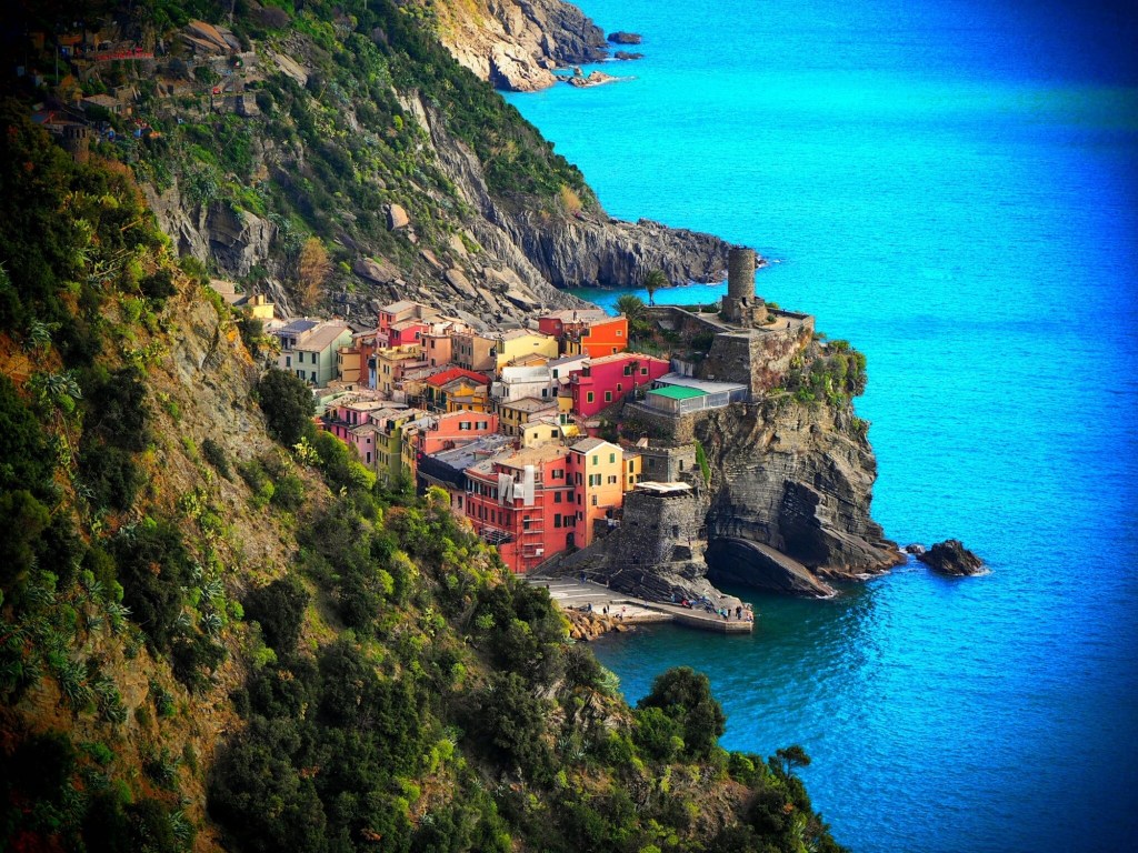 The colorful buildings of Vernazza stand out against the cliffside and stunningly blue water.
