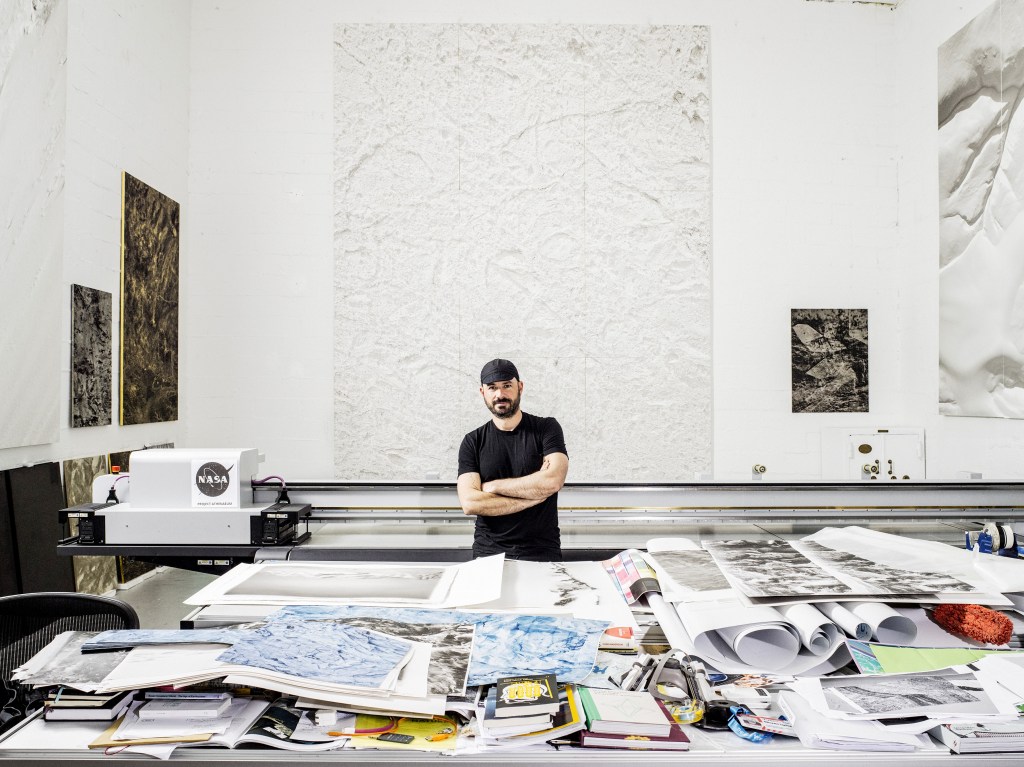 Justin stands near artwork in his studio.