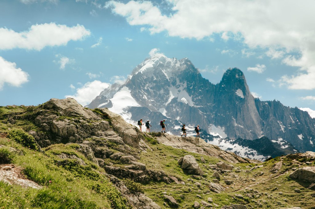 Hikers traverse a ridgeline in the Alps.