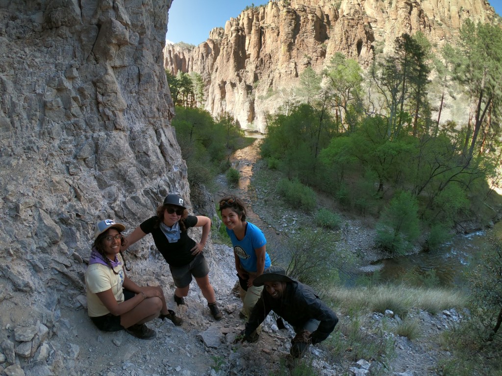 Hikers pose for the camera as the sun sets, reflecting off the walls of the canyon behind them