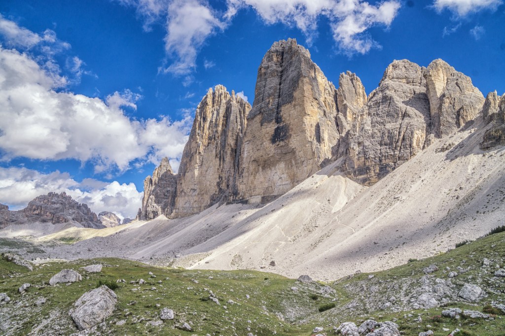 The Tre Cime scrape a blue sky with le large scree slopes below.