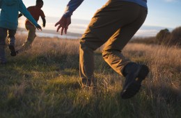 A dad chases two kids on a hike