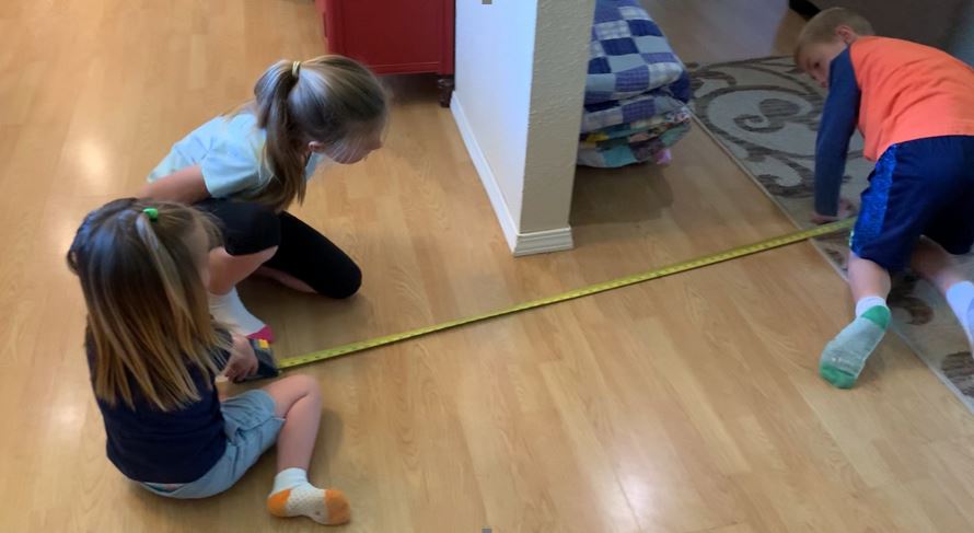 Anna, Jane and Judah measure a section of their home.