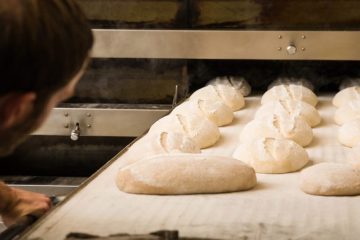 Eric Wolfinger putting unbaked loaves of bread into an oven.