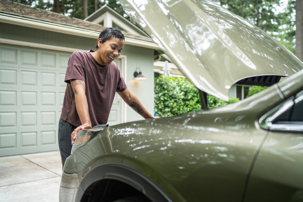 Woman looks at the engine of her vehicle.