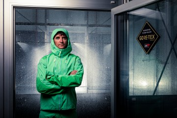 Greg Hill standing in front of the GORE-TEX testing lab in a green rain jacket.