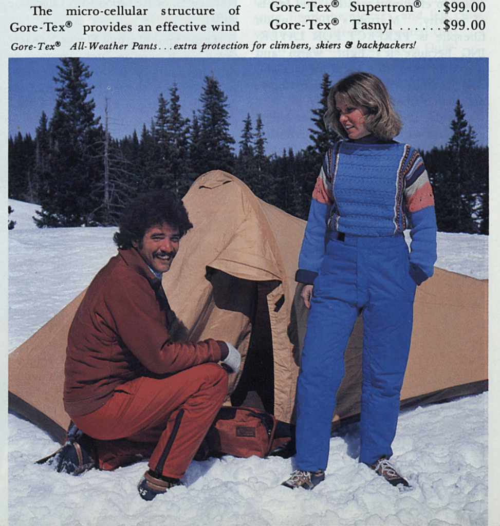 A man and a woman standing next to a tent pitched in the snow.
