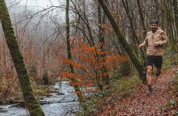 Karel Sabbe is running on a trail next to a river. There is fall foliage in the background and on the ground.