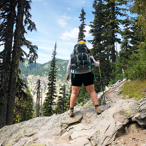 Hiker standing in forest looking out at beautiful scenery.