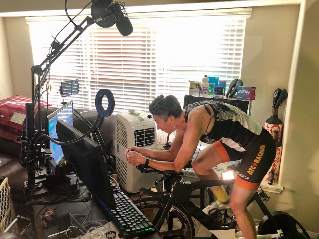 Woman pedaling on indoor bike in front of computer screen.