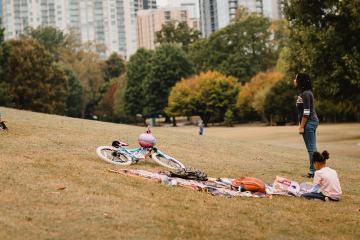 Woman holding frisbee at urban park with two girls nearby.