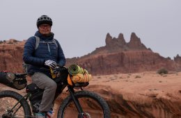 Person standing on bike in desert setting.