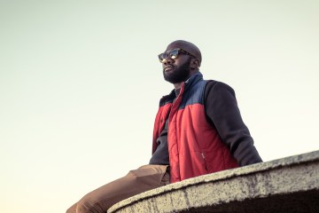 Person wearing sunglasses sitting outside on a ledge