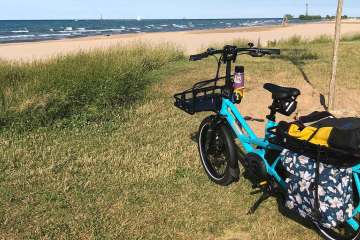 photo of blue ebike on lawn in front of water.