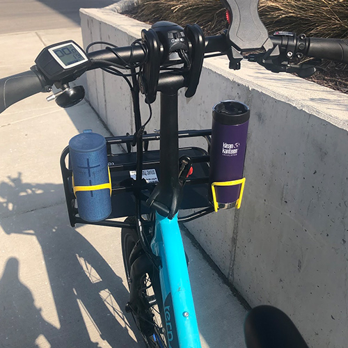 Photo showing a portable music speaker and a water bottle held in the water bottle holders of a bike.