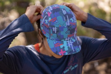 A woman secures a colorful hat to her head before taking off on a trail run