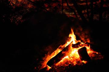 A campfire at night under a dark red sky