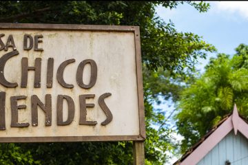 A photo of a blue house with a sign in the foreground that says Casa de Chico Mendes.