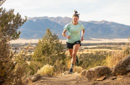 Gina Lucrezi running on a trail. She's wearing a teal shirt and black shorts.