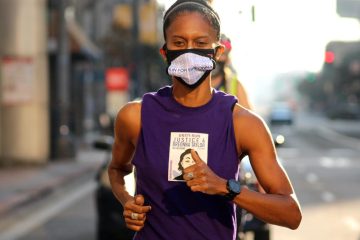 Nicol Hodges is looking at the camera with a purple tank top and a face mask on that says "Breonna Taylor"