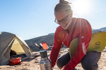 Woman at campsite holds a Big Agnes TwisterCane Biofoam seat pad