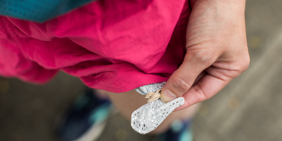 A person is pink baggy running shorts showing how they've rubber-banded their keys in their pocket lining. 