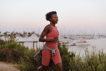 Iman running in a bright workout outfit along a dirt road next to water