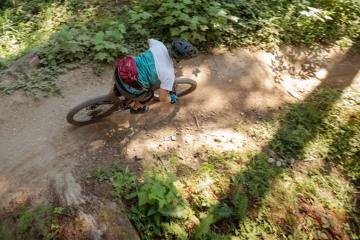 A person rides a mountain bike on a dirt trail in the forest