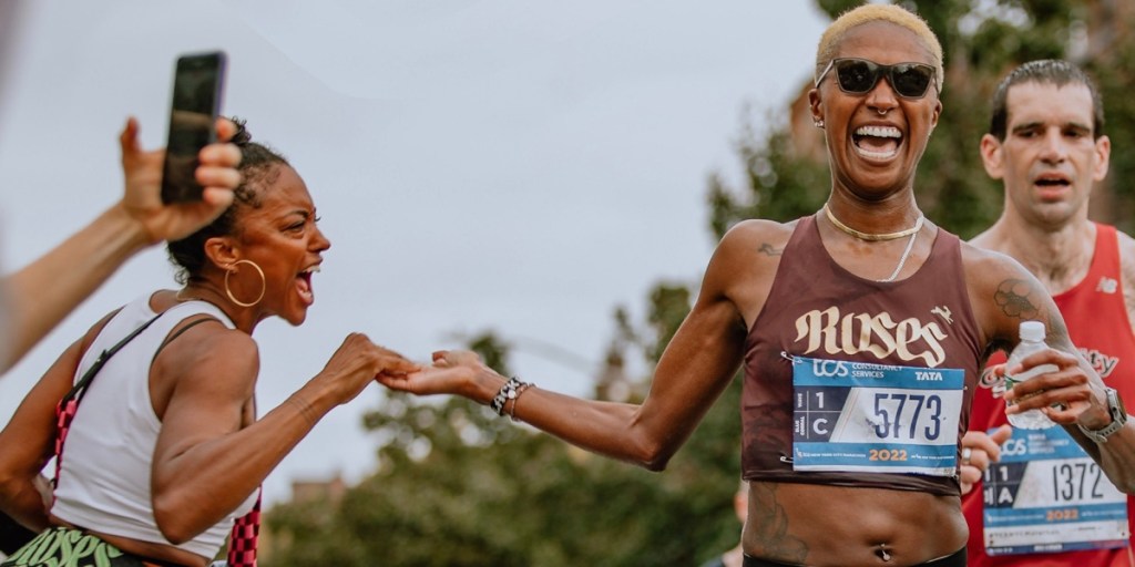 A woman (author Giovanna Fischer) enthusiastically high fives a runner (her teammate Danielle McNeilly) in the middle of a race.