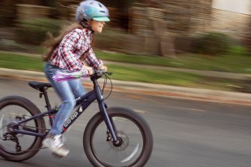 A young cyclist rides the Co-op Cycles REV 20 6-Speed Plus Kids' Bike