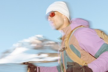 A person holding trekking poles moves along a snowy landscape.