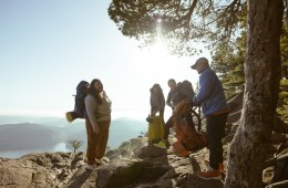 Four people standing on a ridge laughing in the sun