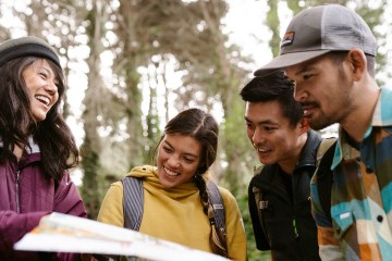 Four people looking at a map in a wooded area