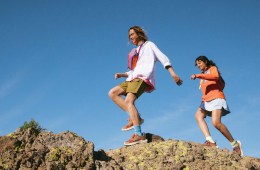 Two smiling hikers on rocky terrain.