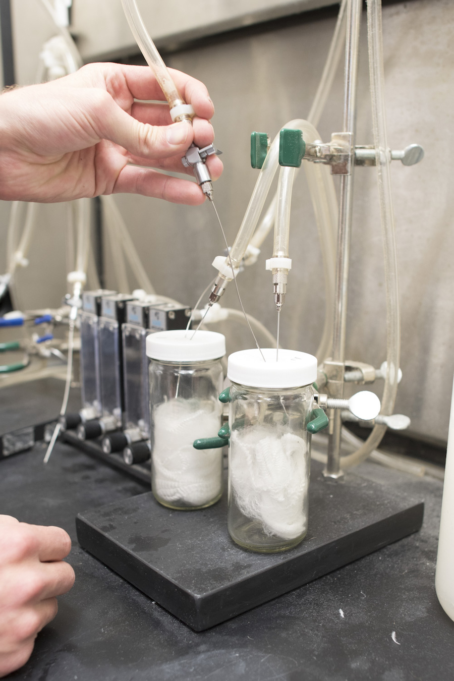 Cocona Labs scientist Taylor Hukari Testing Odor Absorbency in 37.5 fibers. Hukari places a pointy, syringe-like object inside a cylinder which contains 37.5 fibers.