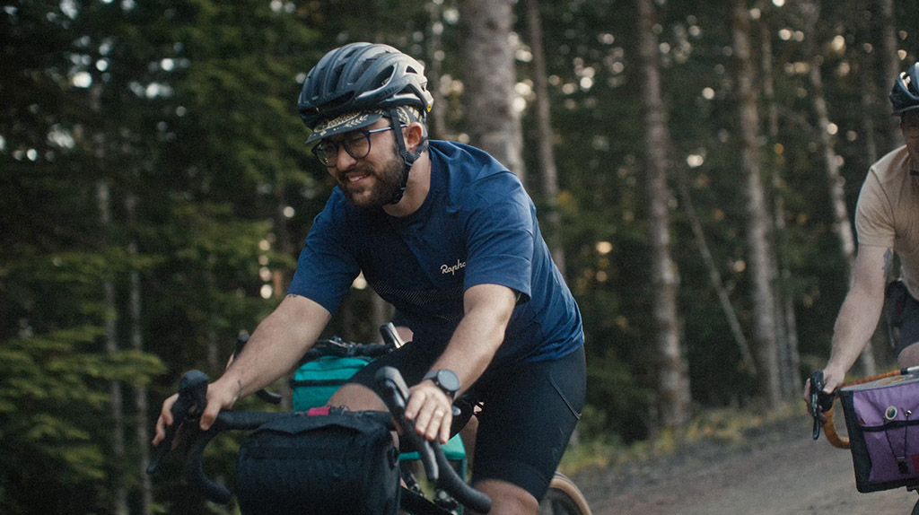 Izzy Sederbaum and a group of friends cycle on gravel in a wooded area.