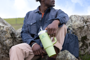 A man holds a light green Stanley Quencher.