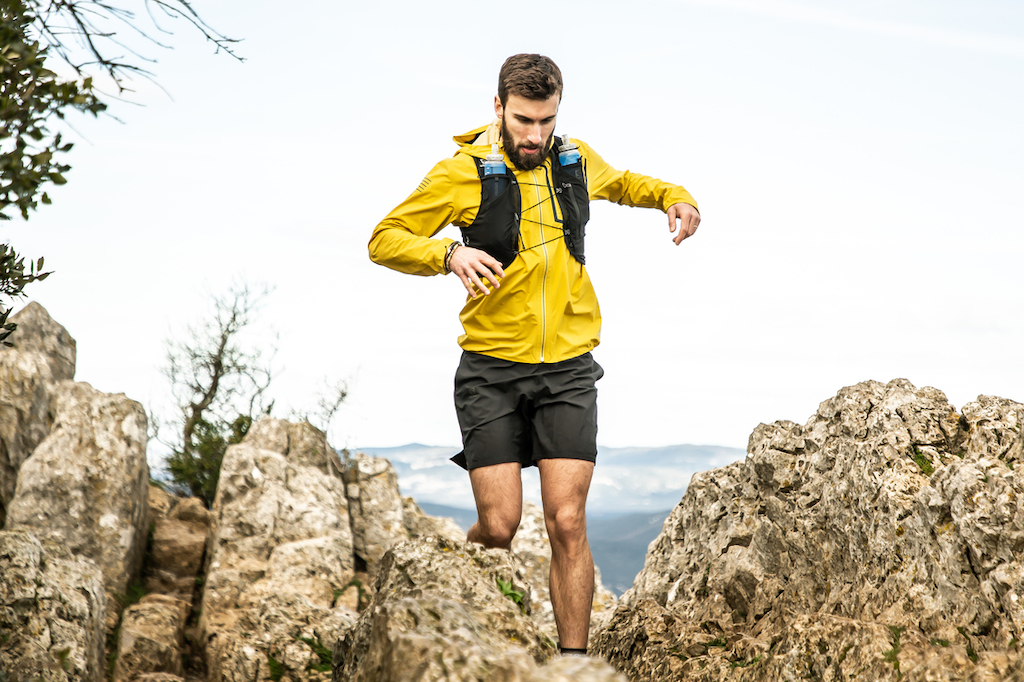 A person running through a mountainous landscape wearing the Salomon Adv Skin 5 Hydration Vest.