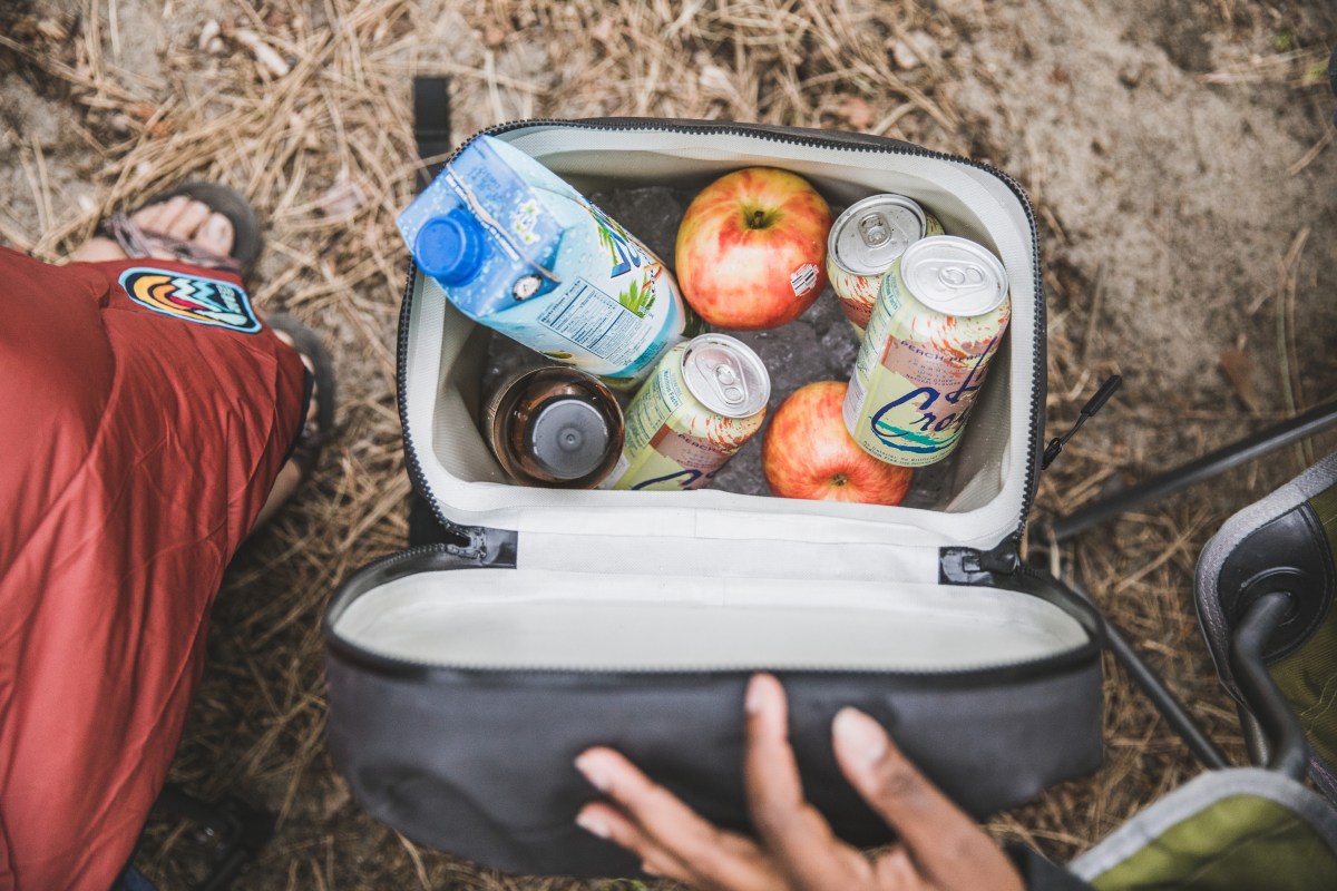 Picture of a small soft-sided cooler filled with ice, apples and drinks.