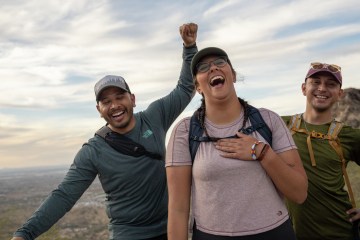 Three people laughing outside on a hike