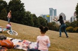 A group of people spend time at the park. Two of the people are throwing a frisbee.