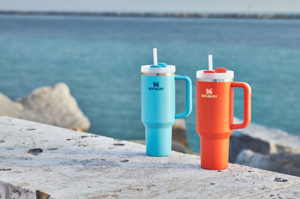 Photo of two Stanley Quenchers near a body of water.