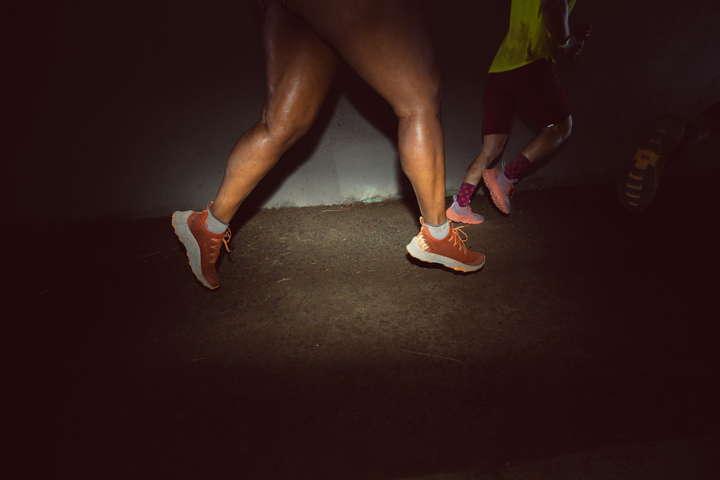 From the legs down, a person running in the Swiftland MT trail running shoes in the colorway Deep Orange.