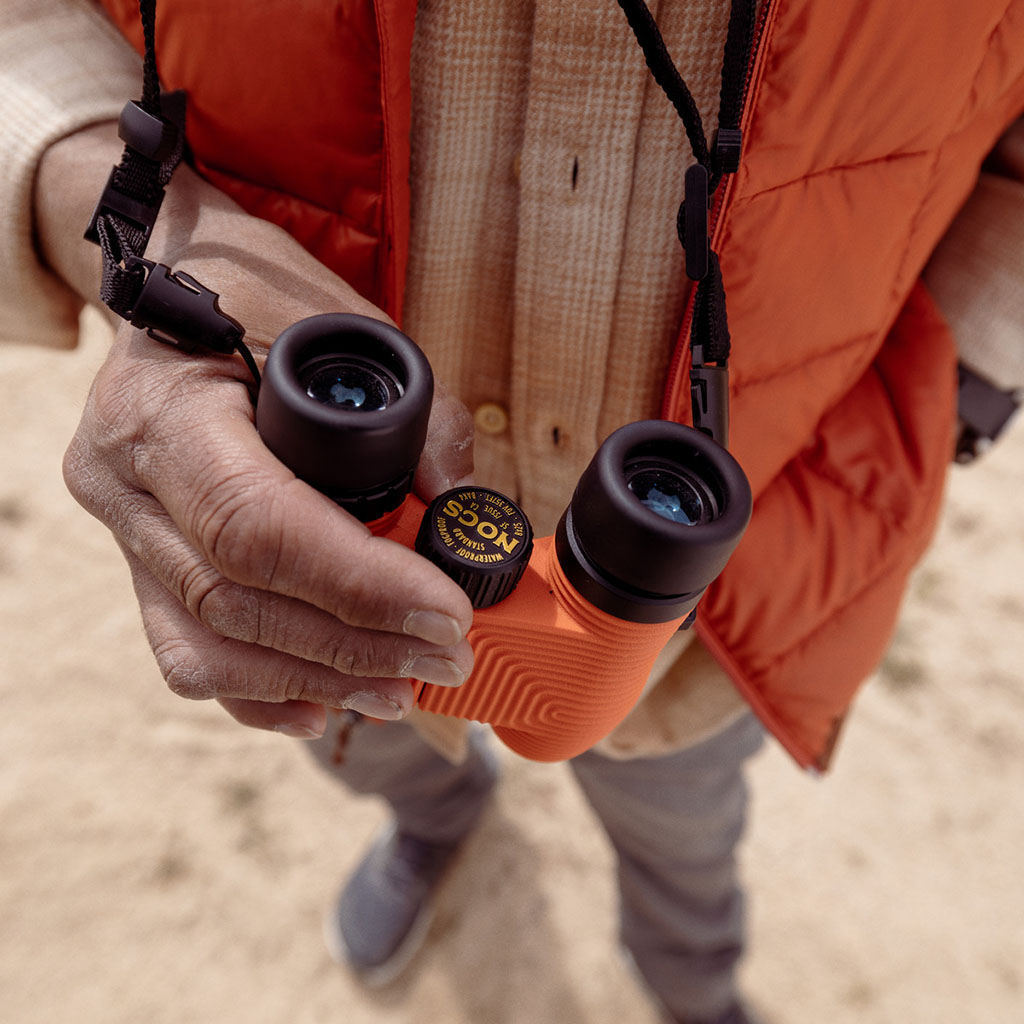 A person holding a pair of Nocs Provisions Standard Issue 8 x 25 Waterproof Binoculars