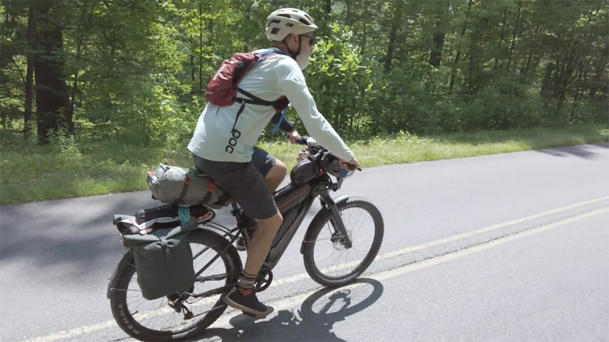 A cyclist wearing a helmet bikes down a road.