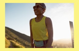 A person in a yellow running tank top and Cotopaxi running belt smiling. A yellow border matching the runner's shirt is framing the photo.