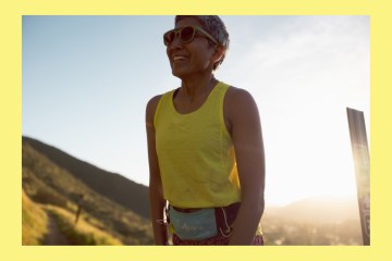A person in a yellow running tank top and Cotopaxi running belt smiling. A yellow border matching the runner's shirt is framing the photo.