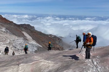 A group of mountaineers at high elevation, above the cloud line.