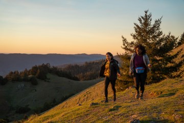 Two hikers walk on a ridge at daybreak